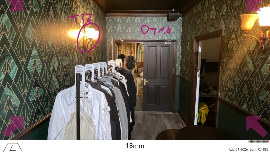 A hallway with patterned wallpaper features a clothing rack filled with garments, a person standing near a doorway, and details from a ZEISS ARRI Alexa Mini LF camera interface overlay.