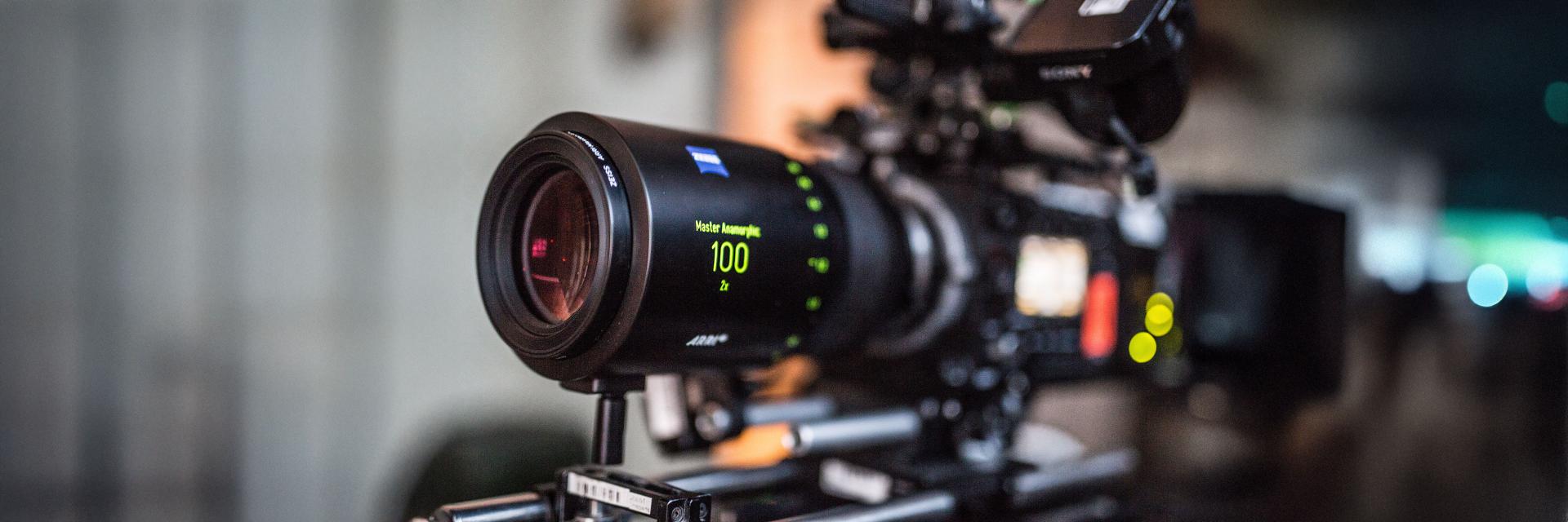 Close-up of a professional cinema camera rig equipped with a ZEISS lens displaying focus and focal length information.