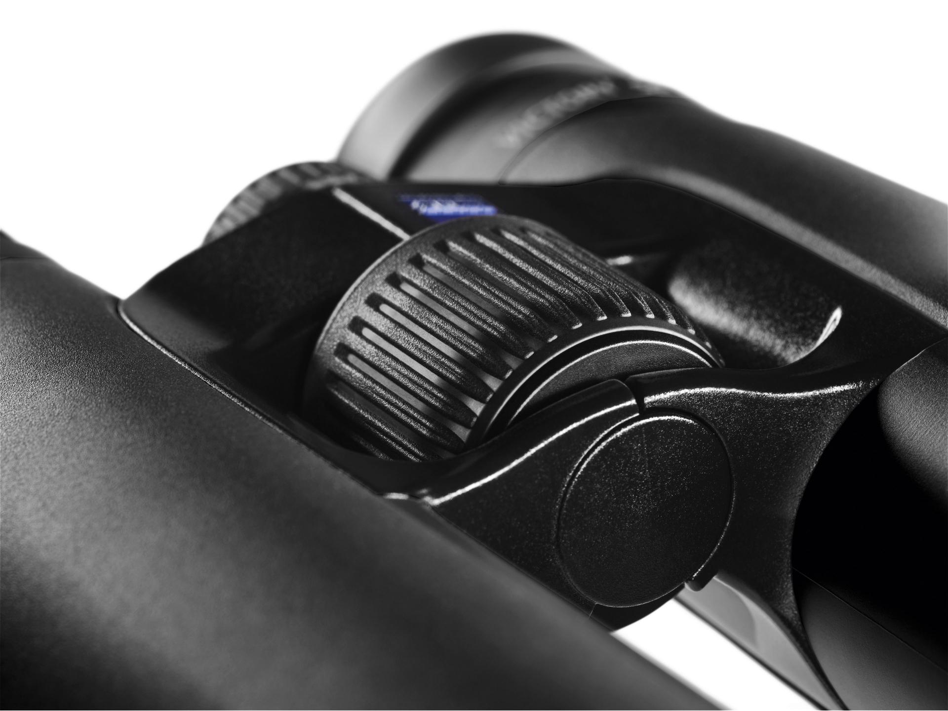 Close-up view of the central focusing wheel on a pair of black ZEISS binoculars.