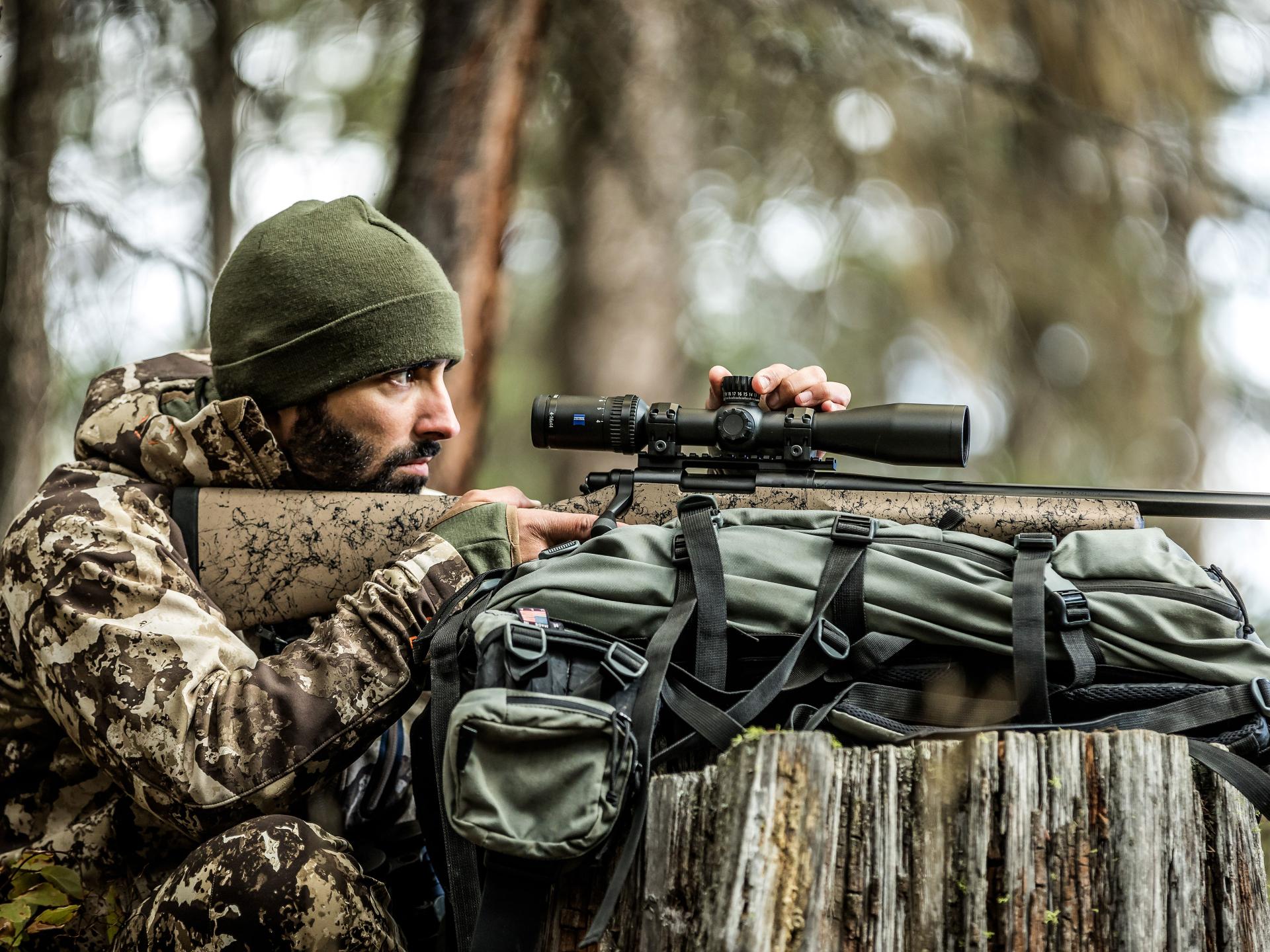 A hunter dressed in camouflage steadies his rifle with a ZEISS Conquest V4 riflescope, highlighting dependable accuracy and control in every hunting environment.