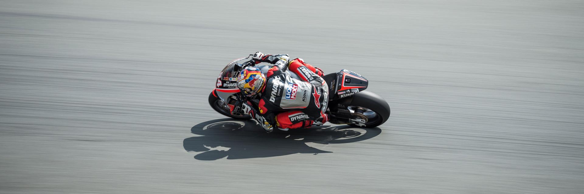 A professional motorcycle racer leans into a turn on a racetrack, captured in sharp detail.