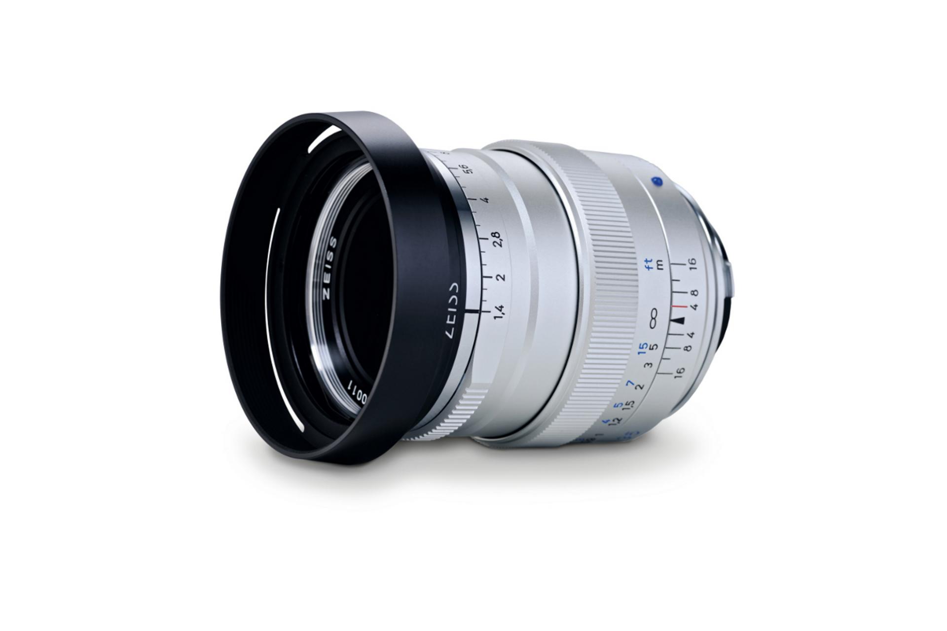 Silver ZEISS camera lens with black lens hood, featuring detailed focus and aperture markings on a white background.