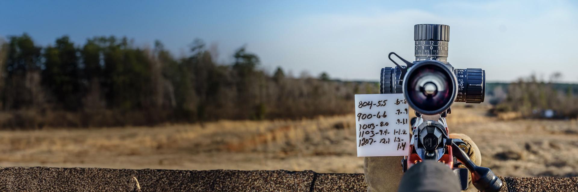 Close-up of a precision rifle scope with adjustment dial and ZEISS branding mounted on a firearm rail system.