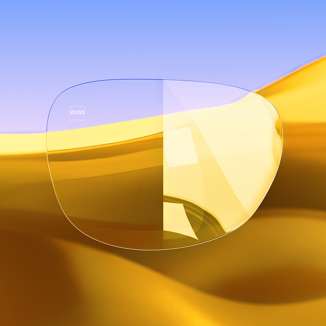 Image fractionnée d’un verre, d’un côté transparent et propre, muni de ZEISS DuraVision Gold UV, et de l’autre côté présentant un reflet lumineux très voyant à sa surface. 