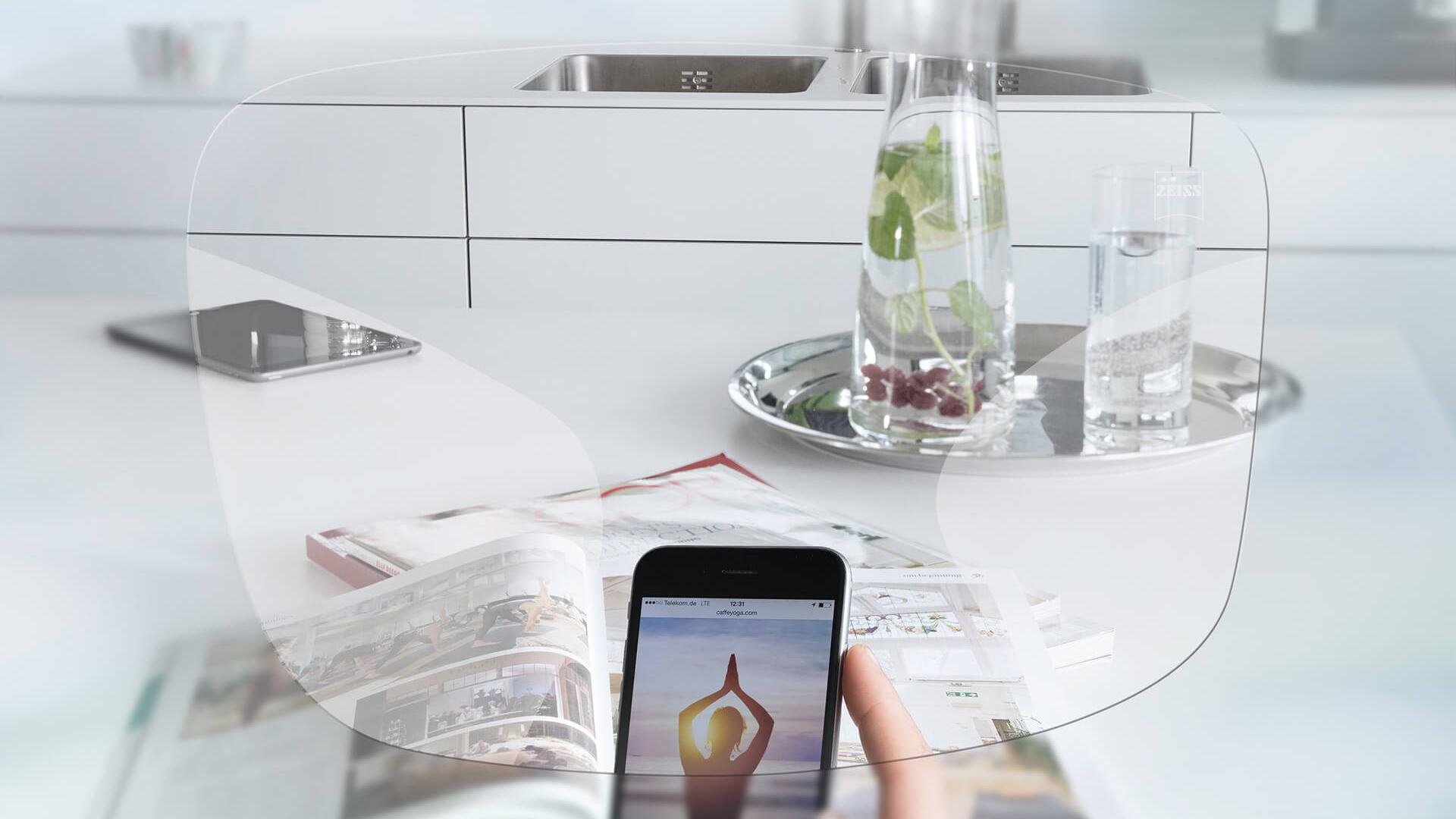 Vue de l’écran d’un smartphone et d’une table de cuisine organisée à travers les verres unifocaux ZEISS EnergizeMe. 