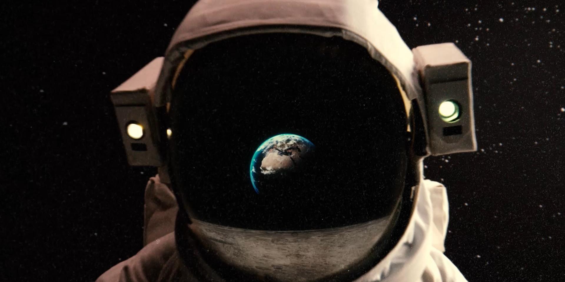 La tête d'un astronaute avec le reflet de la terre et de la lune sur la visière