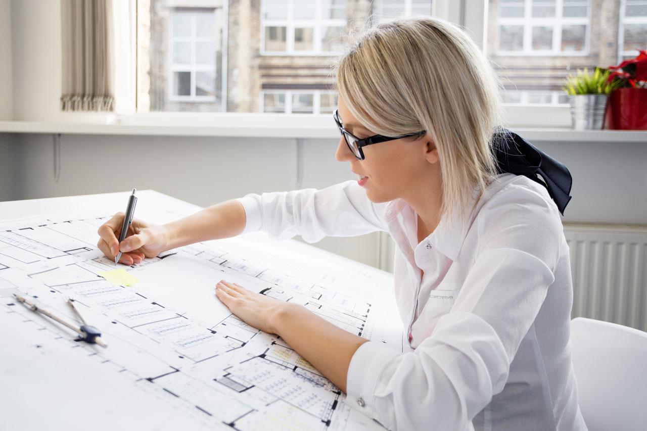 Une jeune architecte portant des lunettes et travaillant à un plan