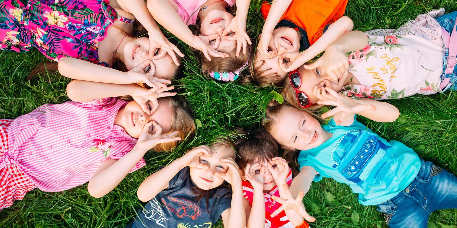 A group of children lying on the green grass in the Park. loremipsum