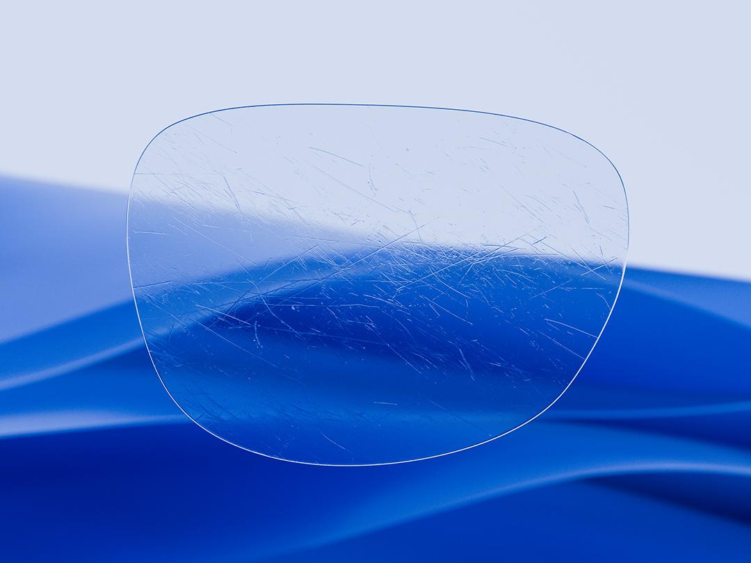 Image divisée en deux montrant une moitié de verre ZEISS caractérisée par sa clarté et sa propreté tandis que l&apos;autre moitié présente un verre de lunettes classique rayé, soulignant le contraste en termes de durabilité. 