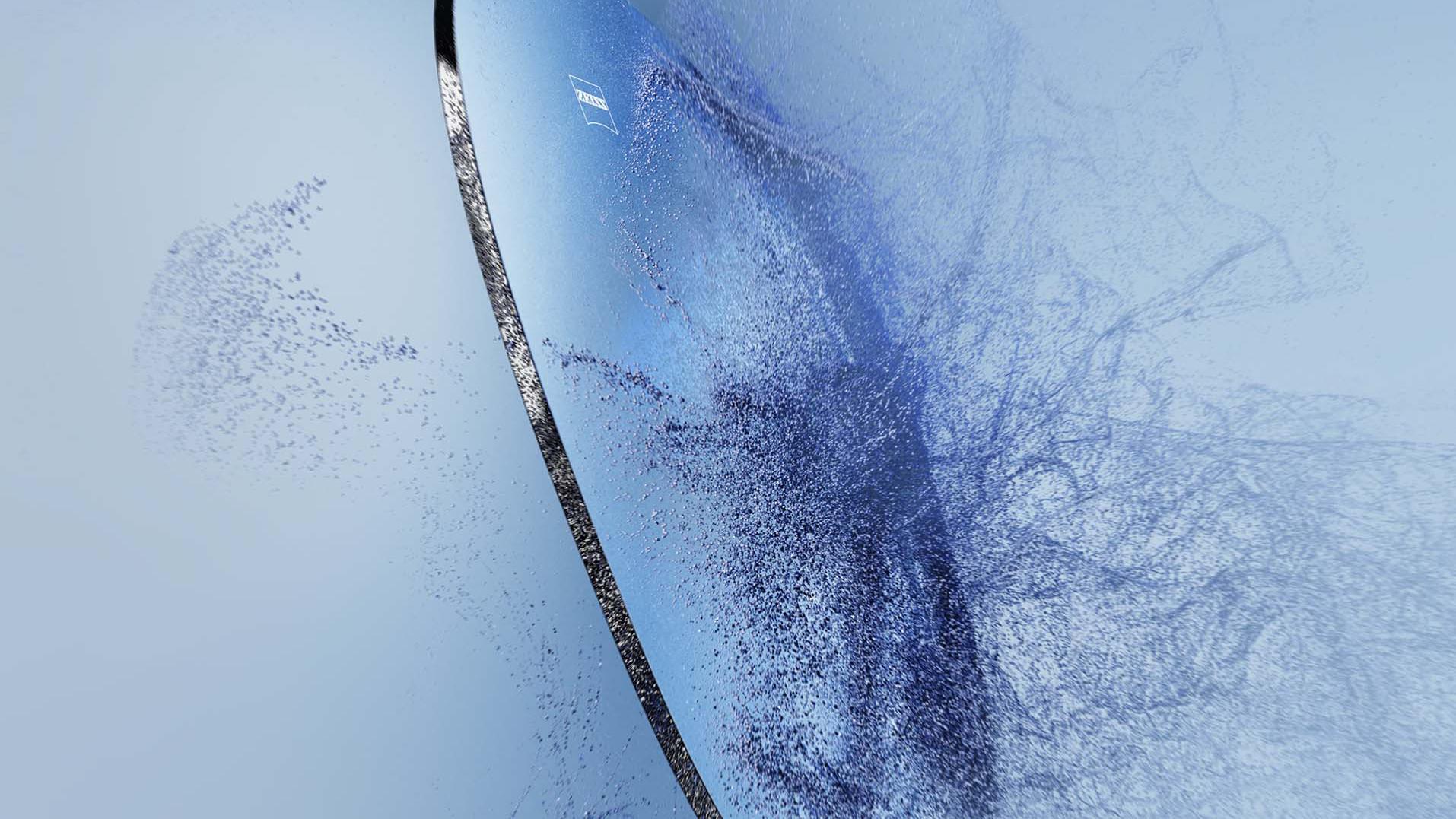 Un verre de lunettes de vue avec le logo ZEISS entre en collision avec du sable.