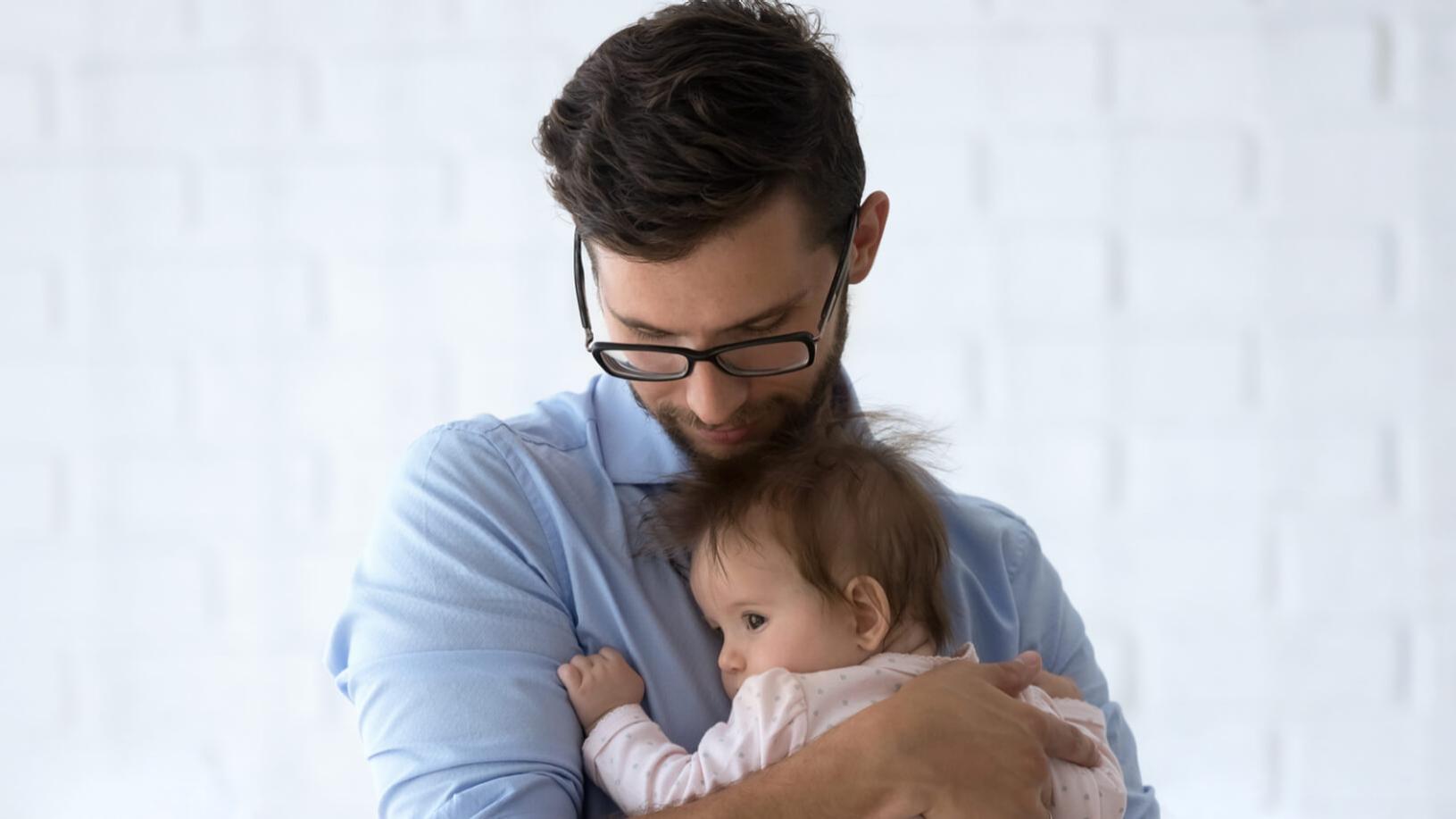 Un homme myope portant des lunettes avec un jeune enfant dans les bras.